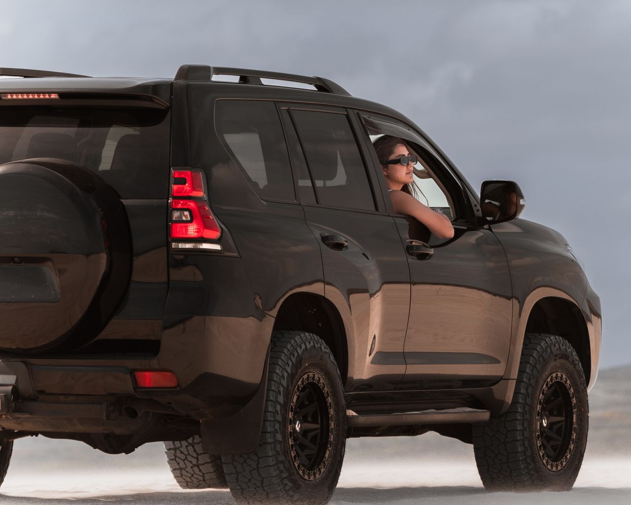 Services A woman enjoys an off-road experience in a rugged SUV in Australia's sand dunes.